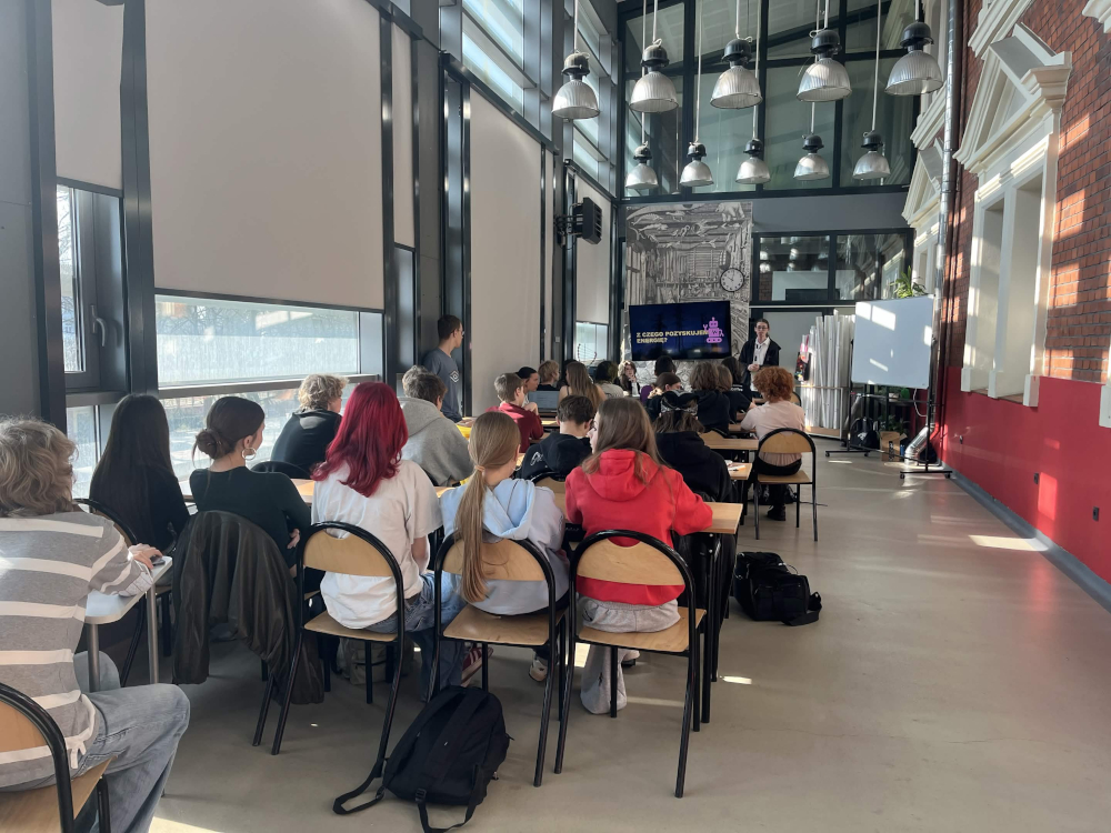 Sala pełna uczniów. Z przodu sali Kamil Kaczyński prowadzi warsztaty.